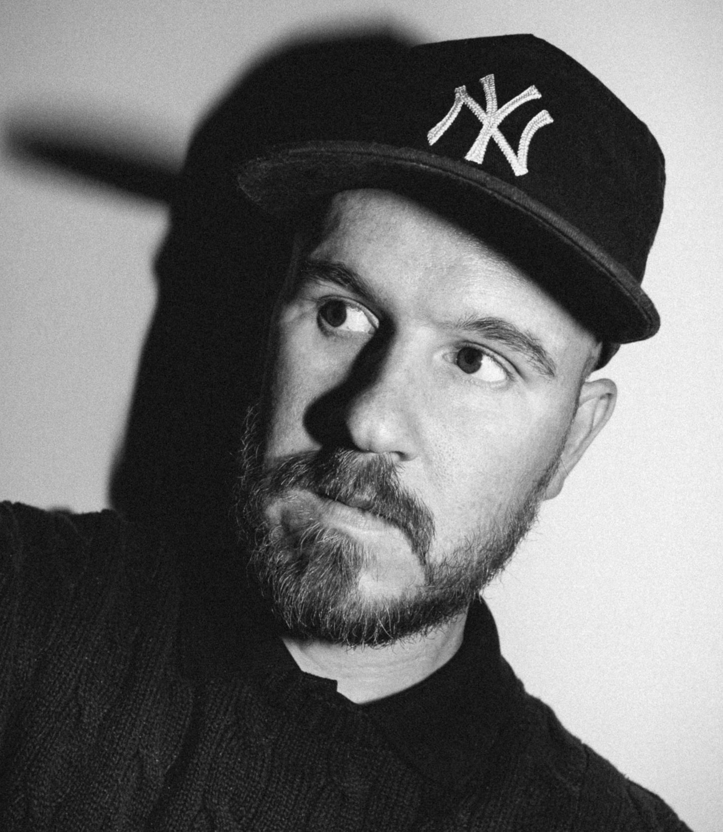 Photographer Jon Premosch, black-and-white portrait in a New York Yankees cap