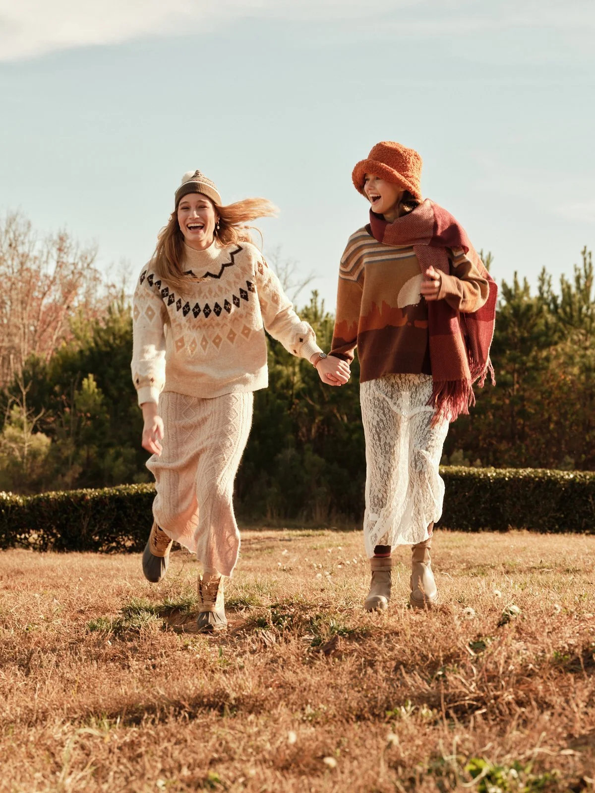 Two women in knitwear walking hand in hand through a field, fall fashion editorial | Jon Premosch, fashion and lifestyle photographer