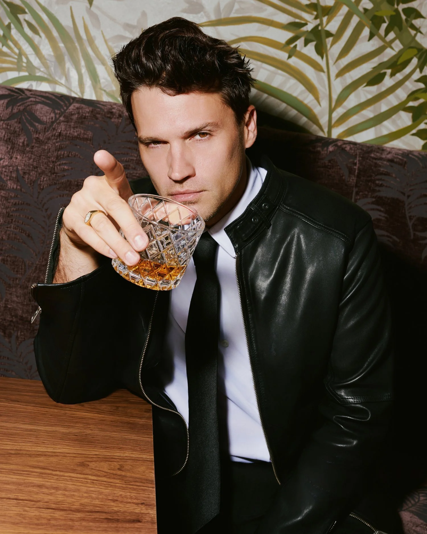 Man in a black leather jacket and tie holding a glass of whiskey, menswear and spirits photography | Jon Premosch, fashion and lifestyle photographer
