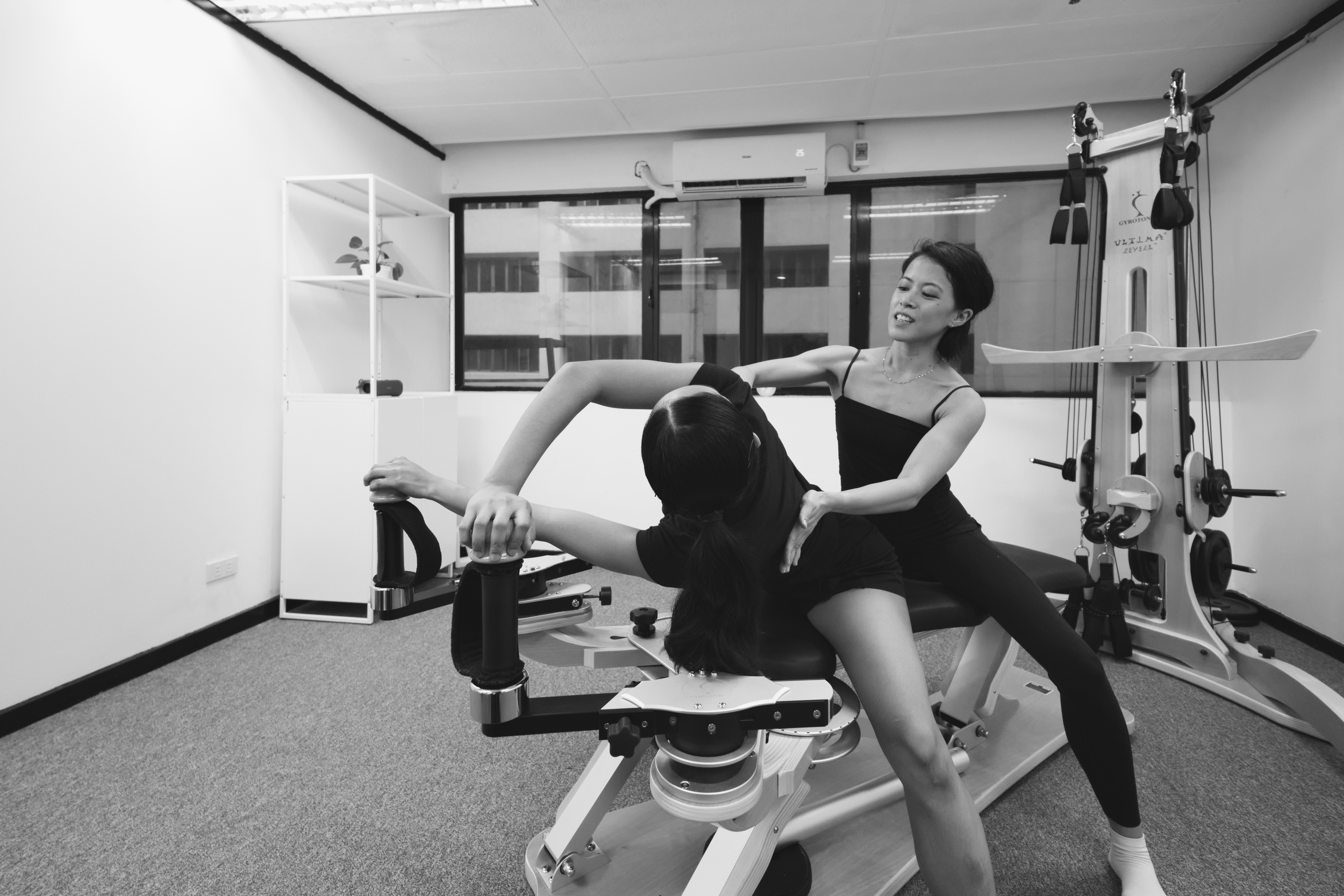 gyrotonic trainer assisting client in mobilizing spine in rotation