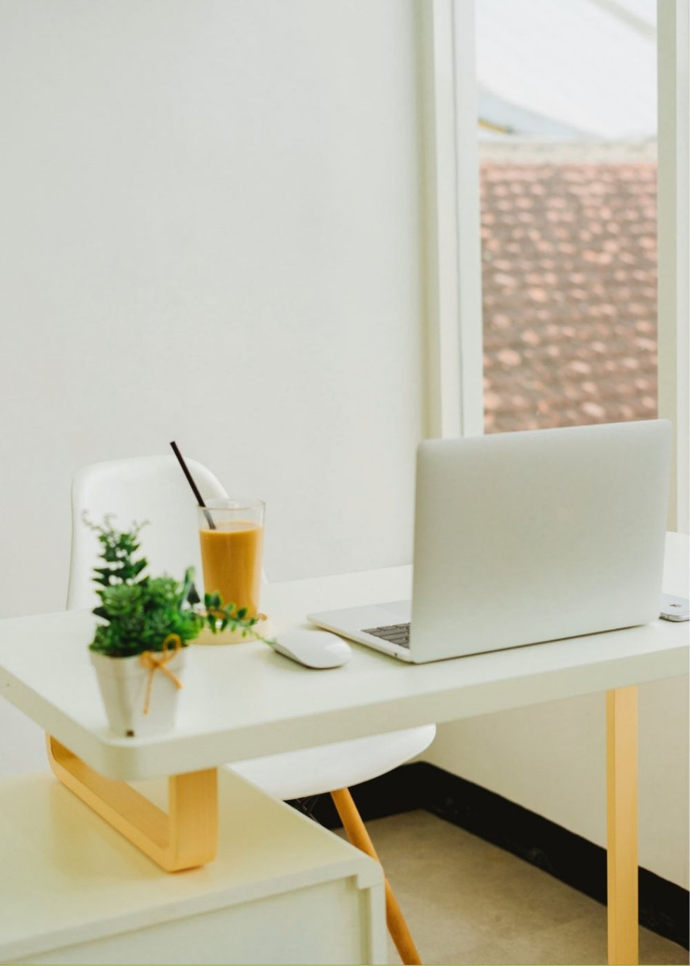 Bright, welcoming therapy workspace with a laptop, desk, and plant.