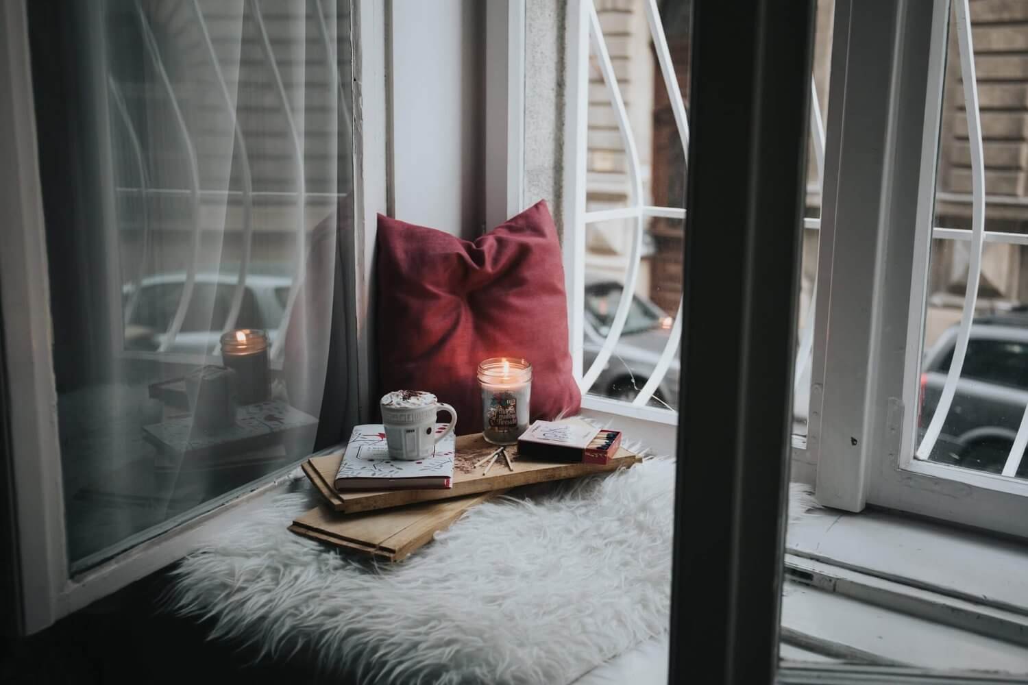 Cozy window nook with a pillow, blanket, and candle, creating a comforting space that symbolizes self-compassion and rest