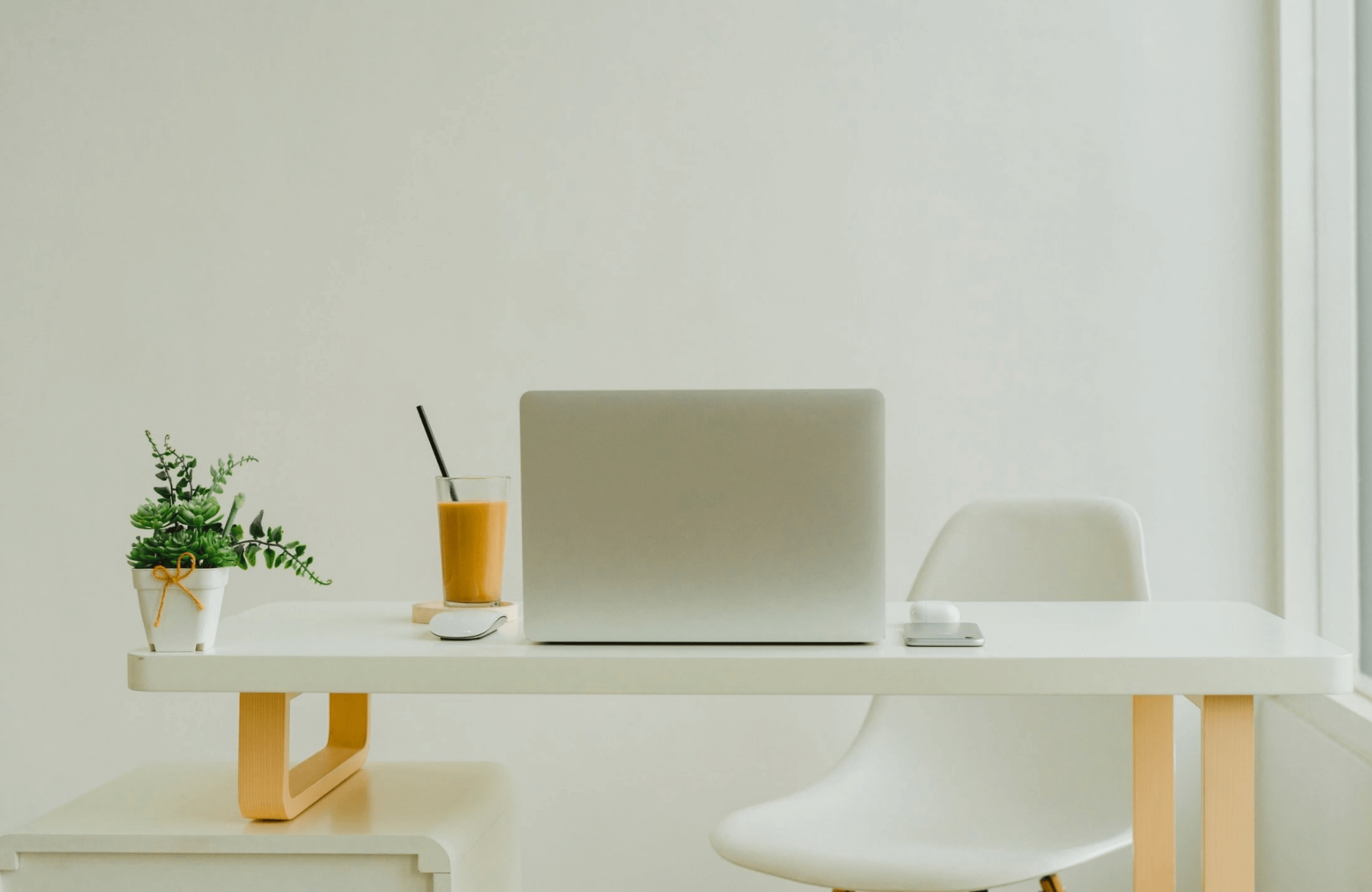 Minimal desk with a laptop, plant, and coffee in a bright room, representing a calm and supportive environment for high-functioning anxiety therapy