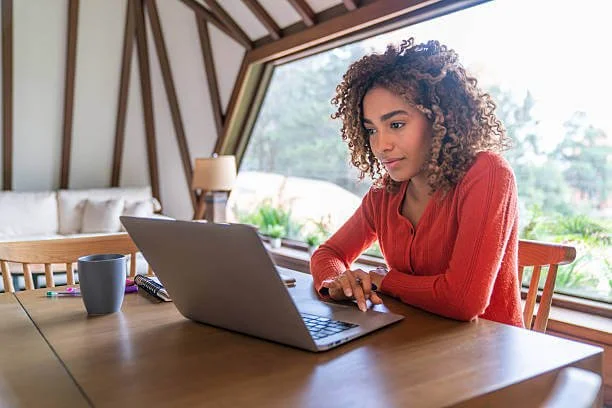 Woman with high-functioning anxiety working on a laptop at home, appearing focused and thoughtful in a calm, natural setting.