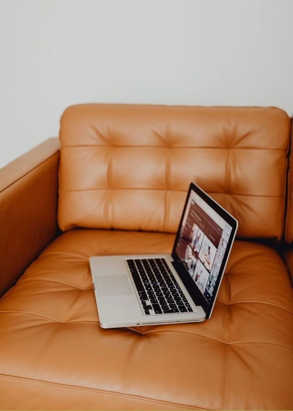 Open laptop on a tan leather chair representing the first step in starting therapy.