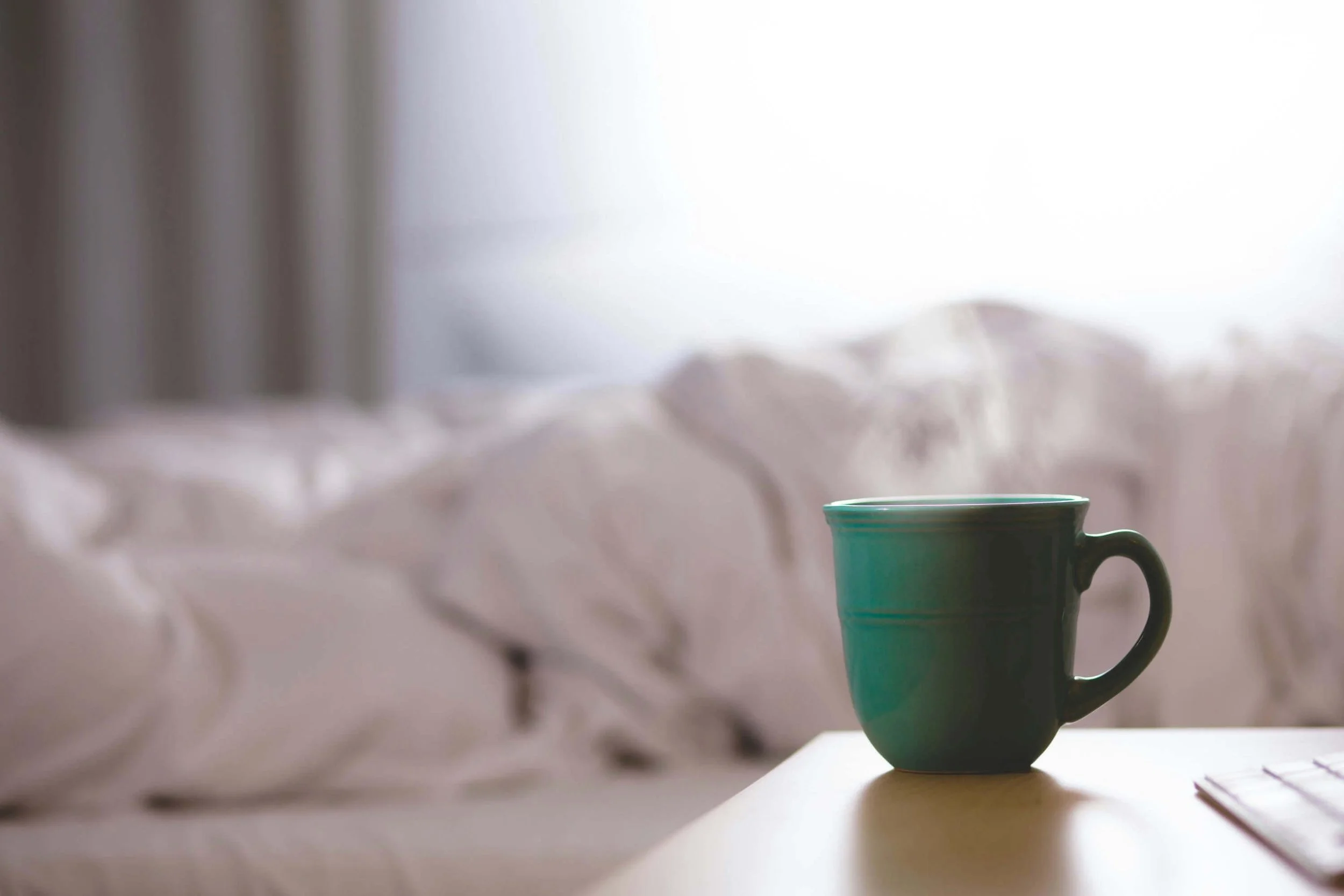 Warm mug of coffee on a cozy blanket, representing rest, emotional safety, and nervous system regulation.
