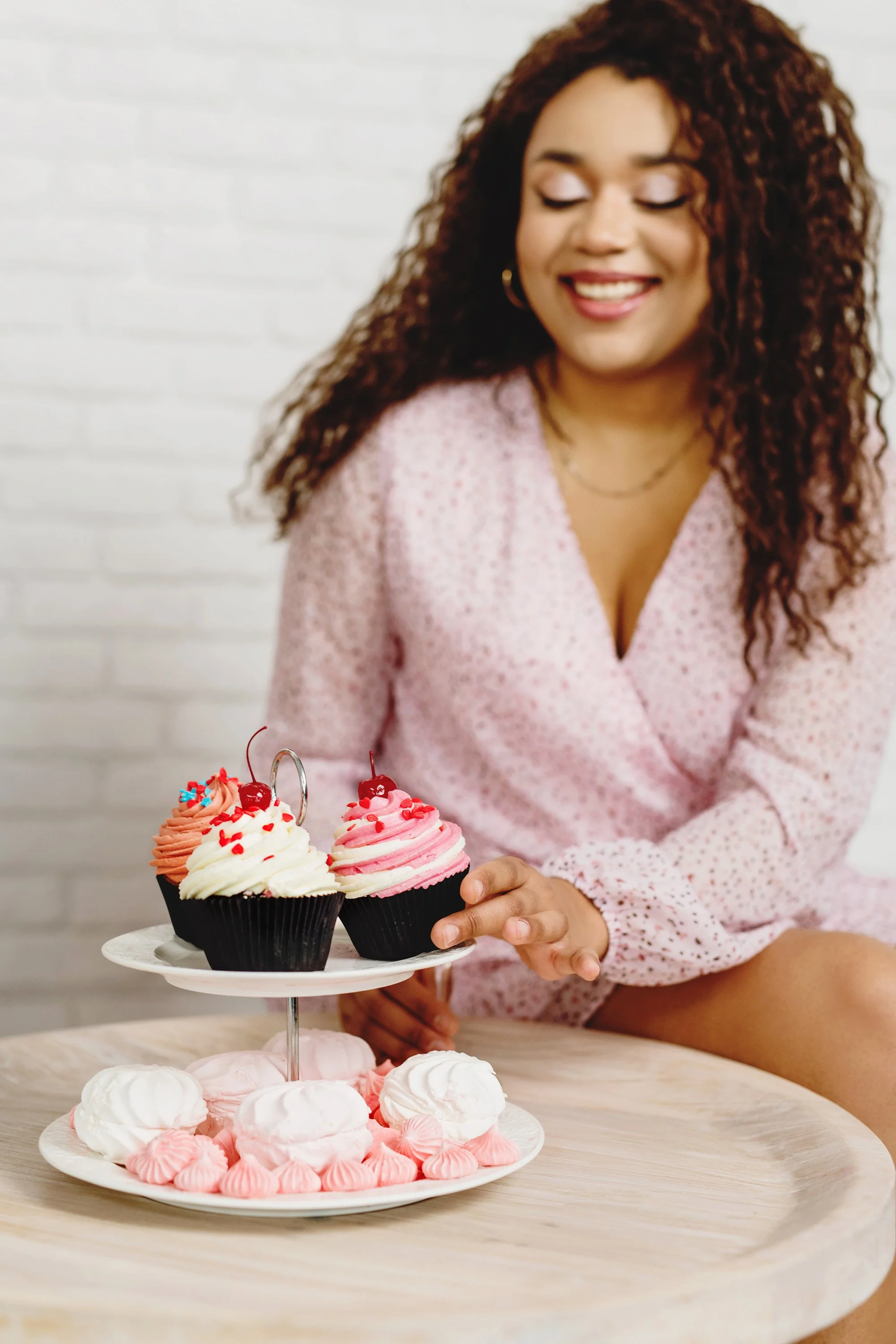 woman placing chocolate cupcakes on tiered cake tray for birthday party