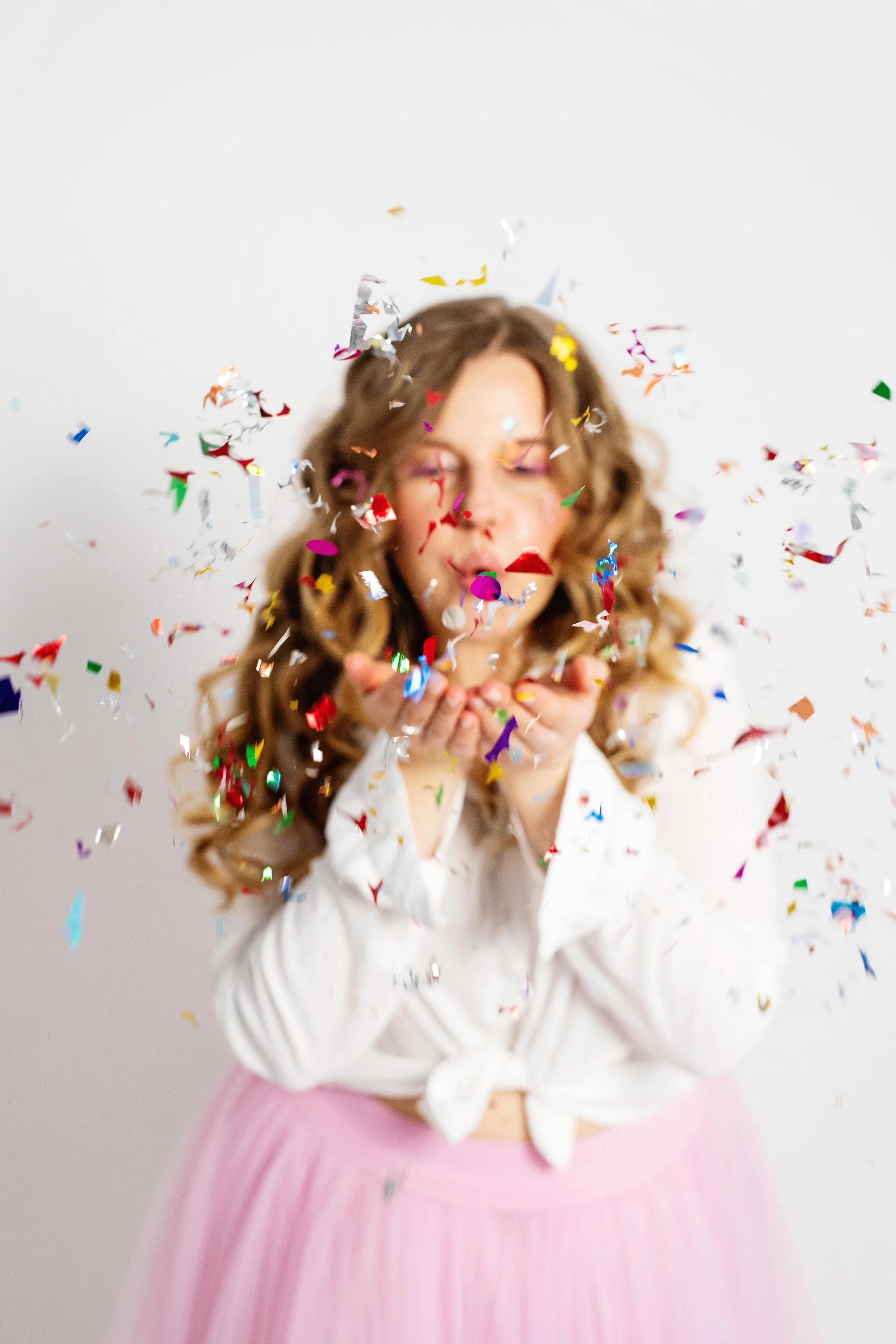 woman blowing colorful confetti out of her hands