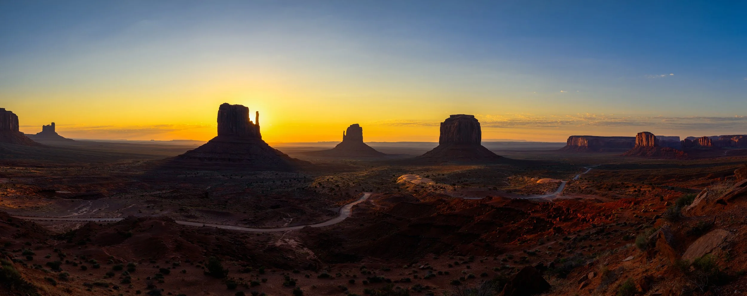 Sunrise over Monument Valley with iconic flat-topped mesas and buttes in the desert landscape.