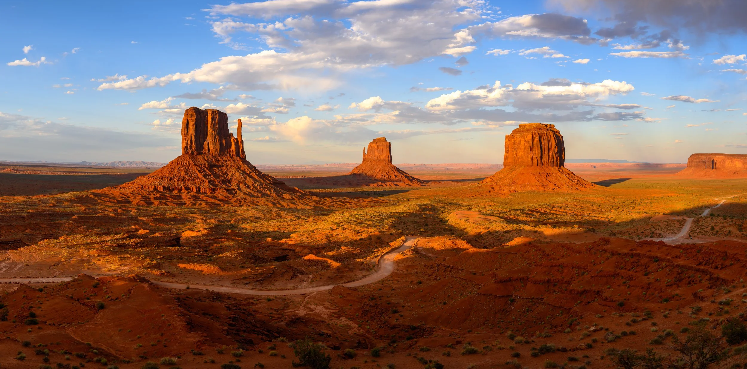 Sunset over the Monument Valley with three prominent sandstone buttes rising from the desert in Arizona.