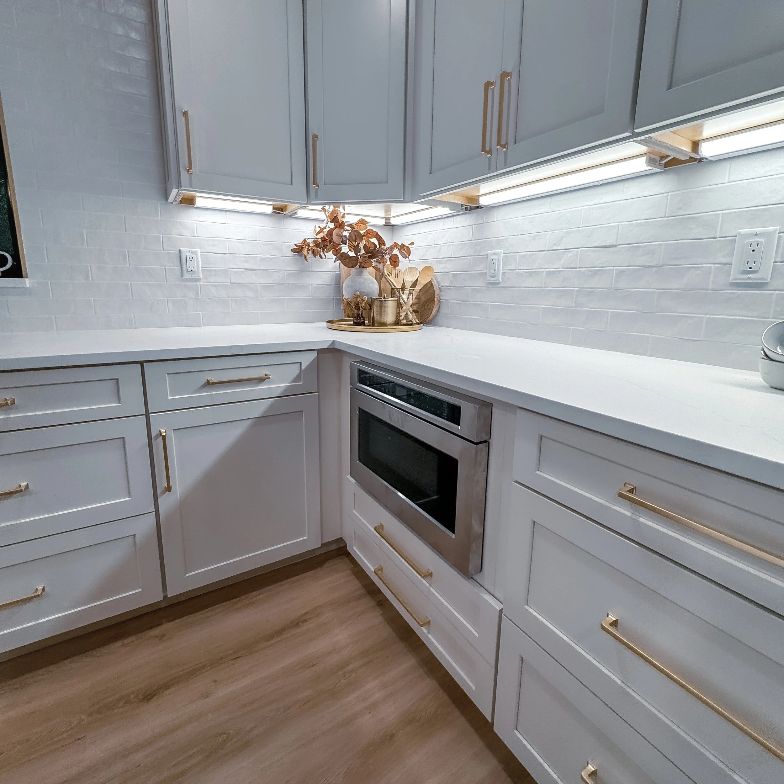 White cabinets with gold hardware and undercabinet lighting. Built by Stellaris Build Co.