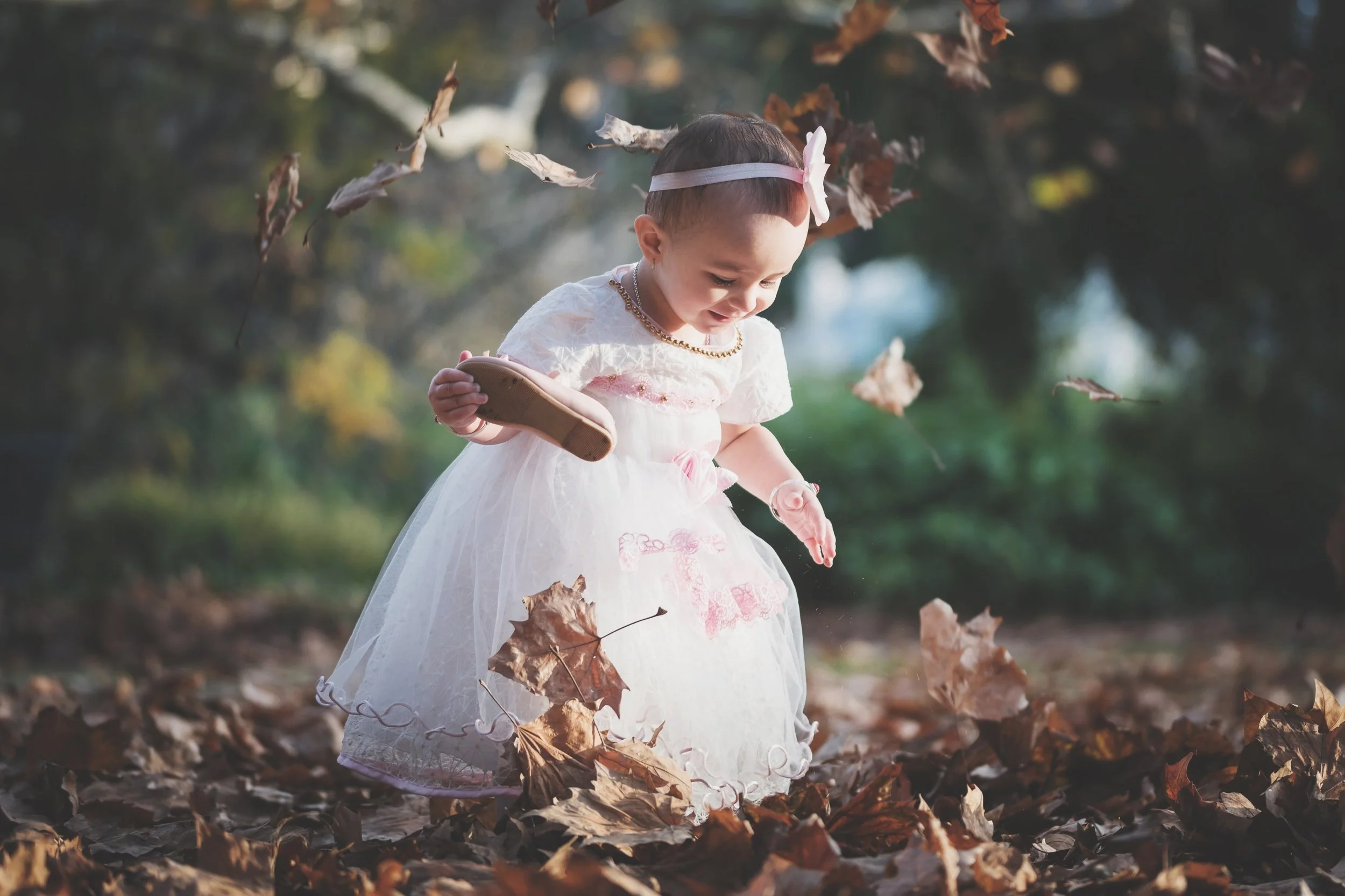 Young daughter playing with autumn leaves in the Adelaide Botanic Gardens