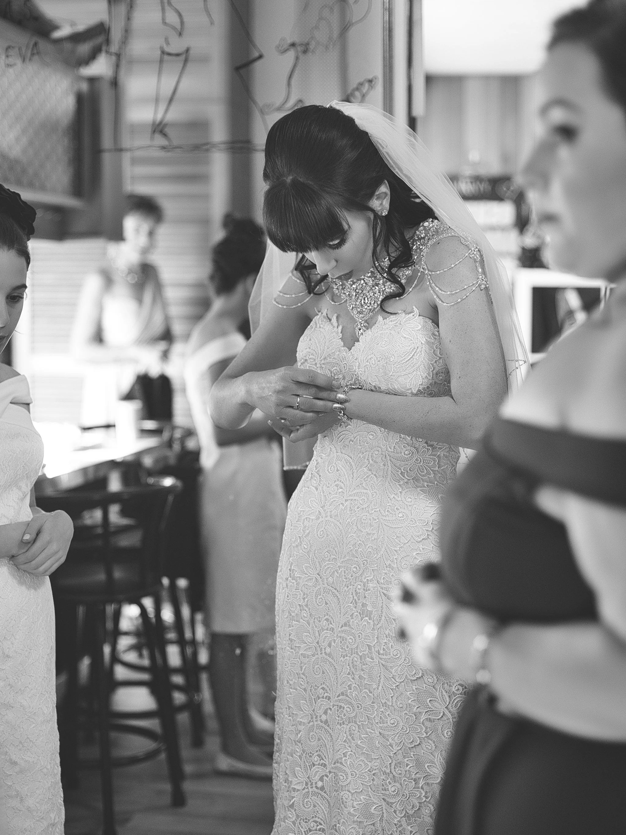 Bride putting on a bracelet surrounded by the bridal party