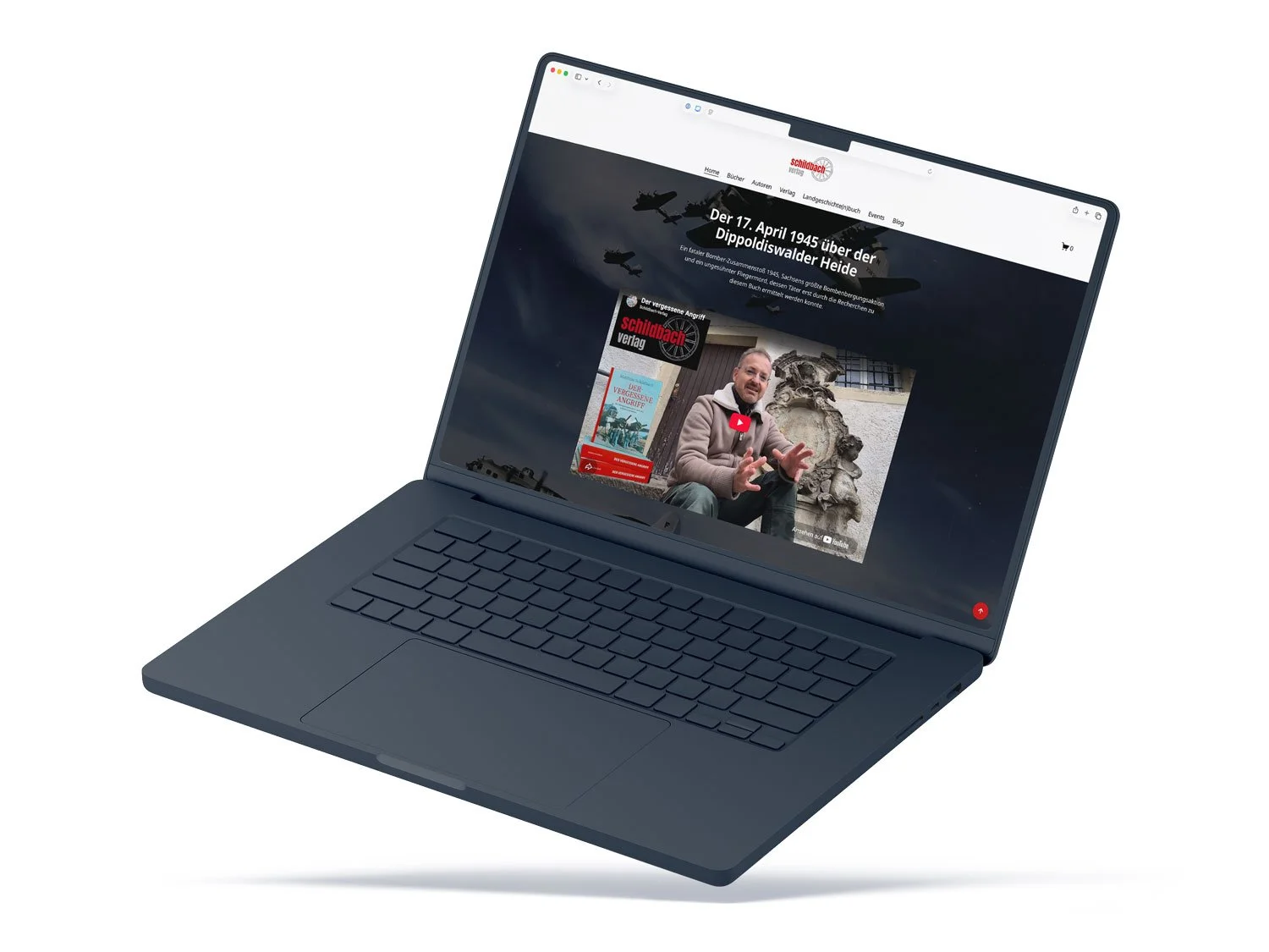 Ein dunkelblauer Laptop präsentiert eine redaktionelle Buchseite des Schildbach Verlags mit eingebettetem YouTube-Videobeitrag und thematischem Hintergrund.