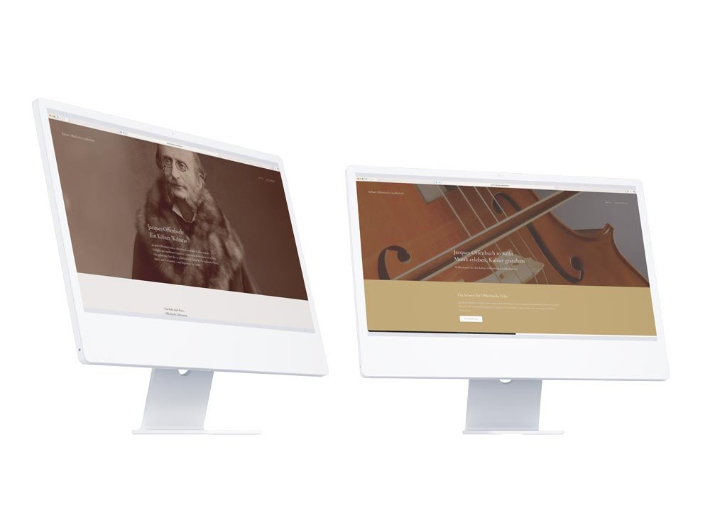 Professionelles Desktop-Webdesign für die Kölner Offenbach-Gesellschaft auf zwei weißen Monitoren. Minimalistisches, großflächiges Design mit historischer Typografie und klarer Content-Ordnung für ein barrierearmes Kulturerlebnis.