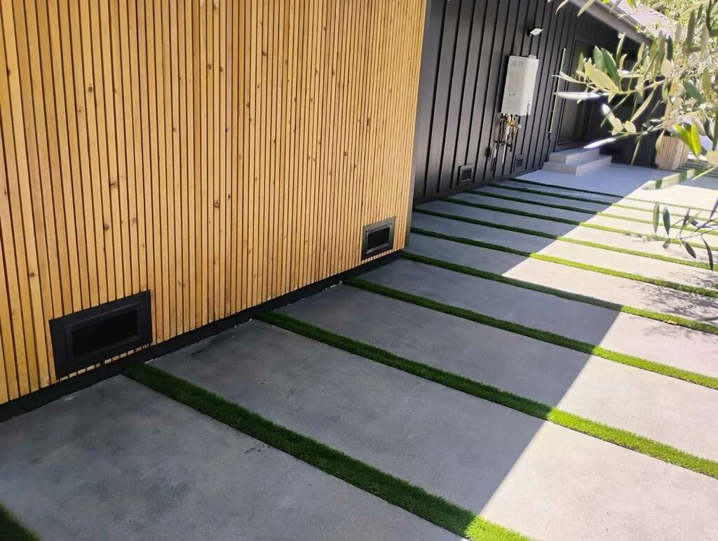 Vents or HVAC grille on exterior concrete wall next to a metal fence