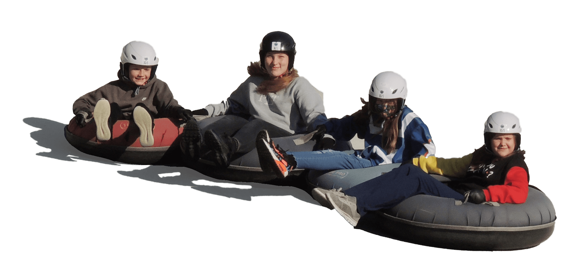 Four children wearing helmets and warm clothing, sitting on an inflatable tube ready for tubing down a snow-covered hill.