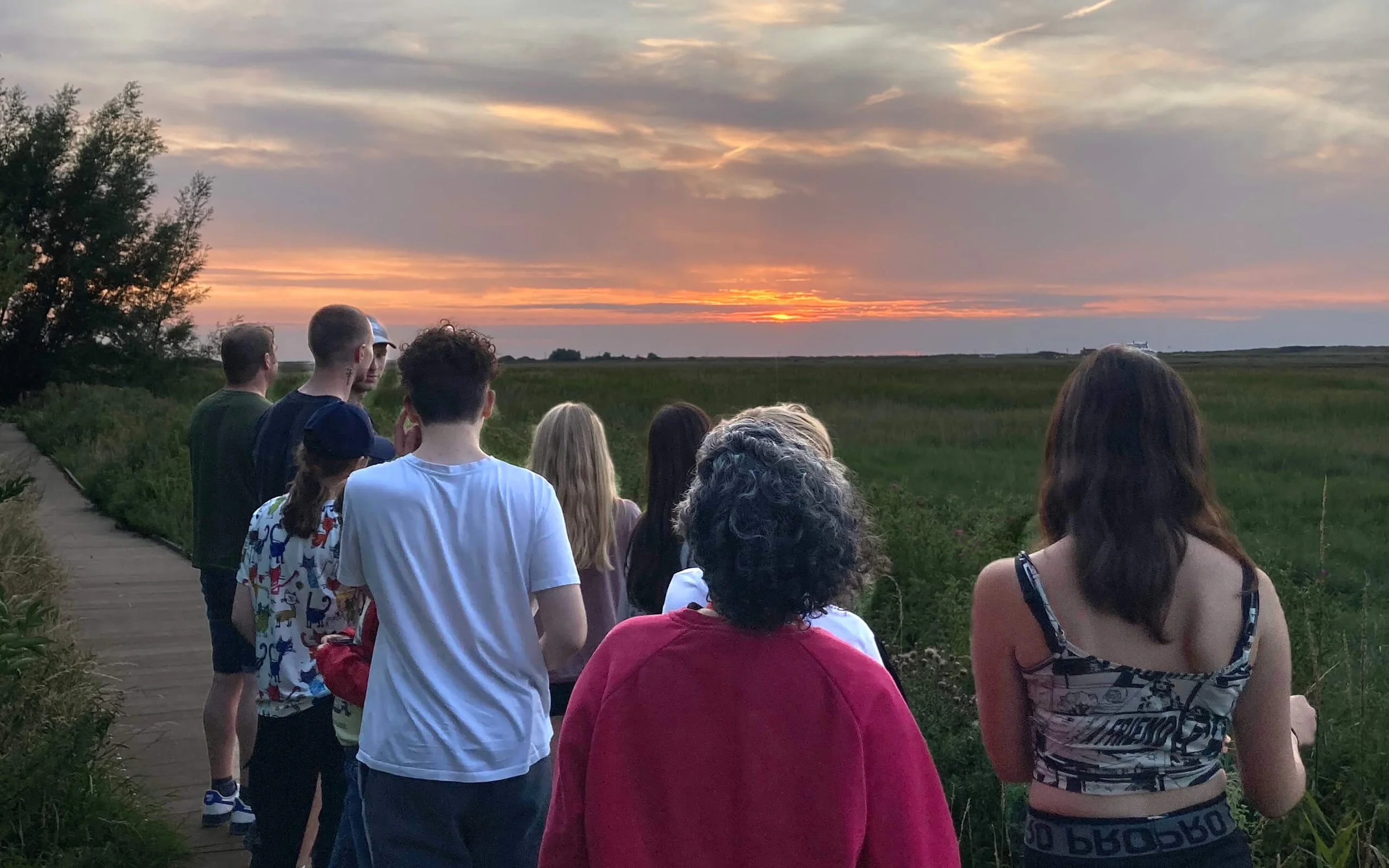 Group of people watching a sunset over a marshy area