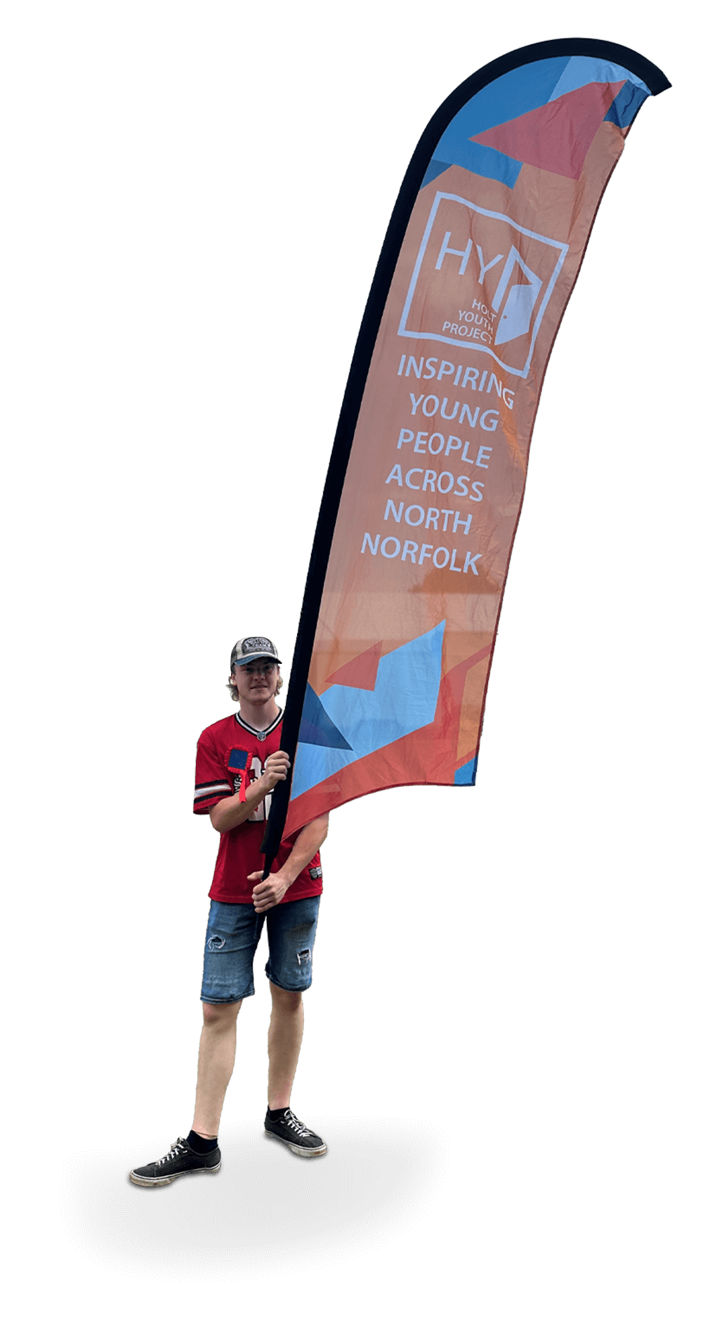 A young person holding a large, colorful flag with the text 'Inspiring Young People Across North Norfolk' and the logo of 'HYP' or 'Holt Youth Project'.