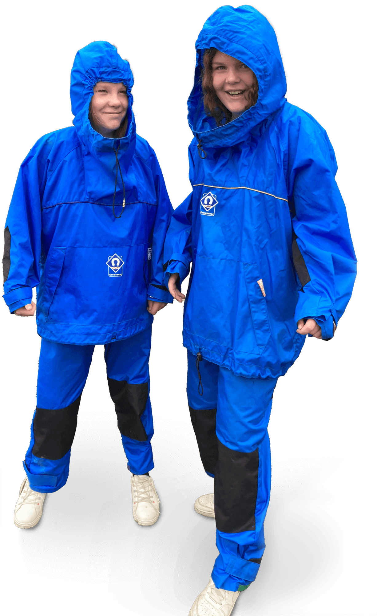 Two children dressed in blue waterproof rain jackets and pants, smiling and holding hands, with a black background.