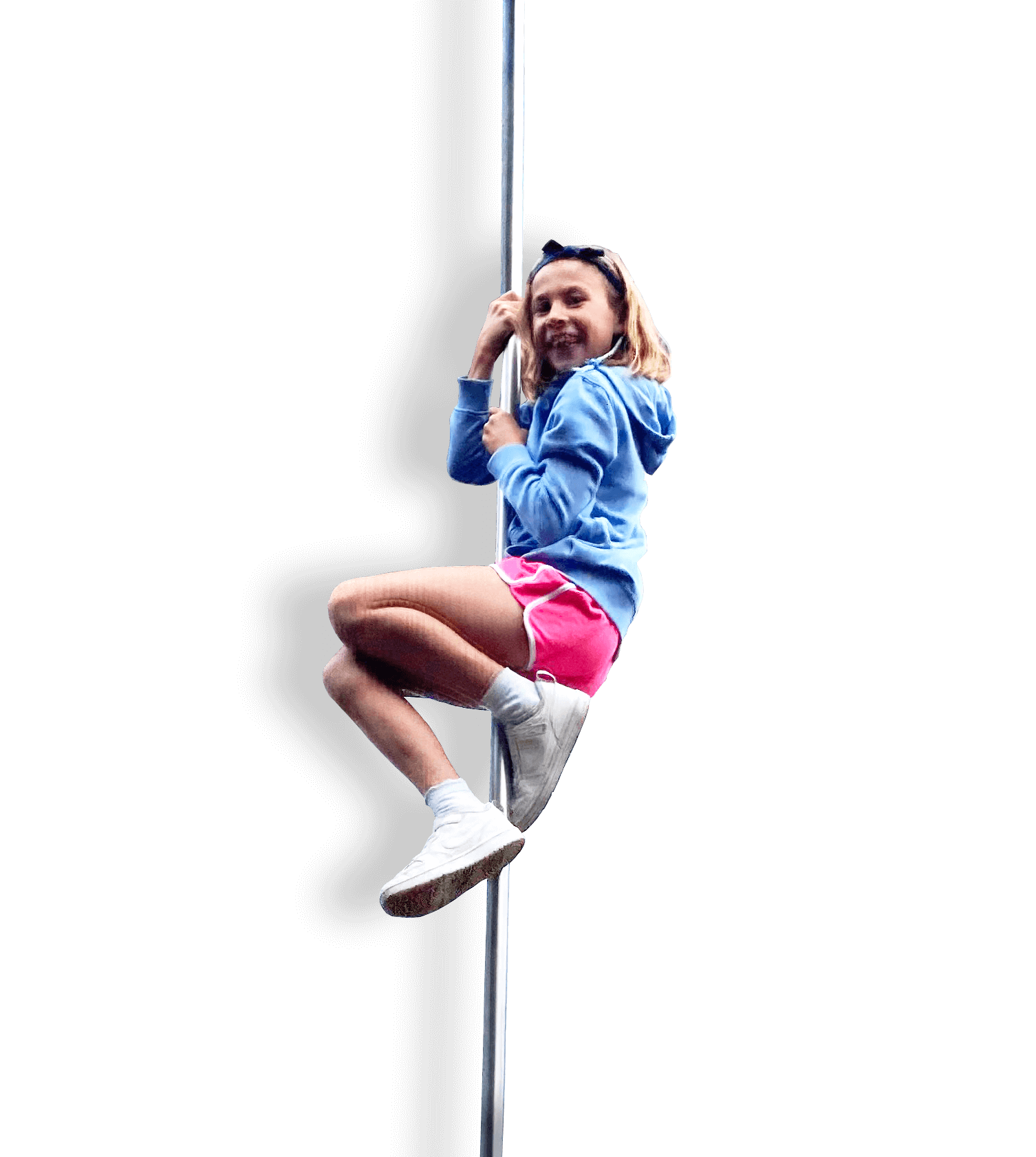 A girl with long hair, wearing a light blue hoodie, pink shorts, and white shoes, climbing a pole and smiling.