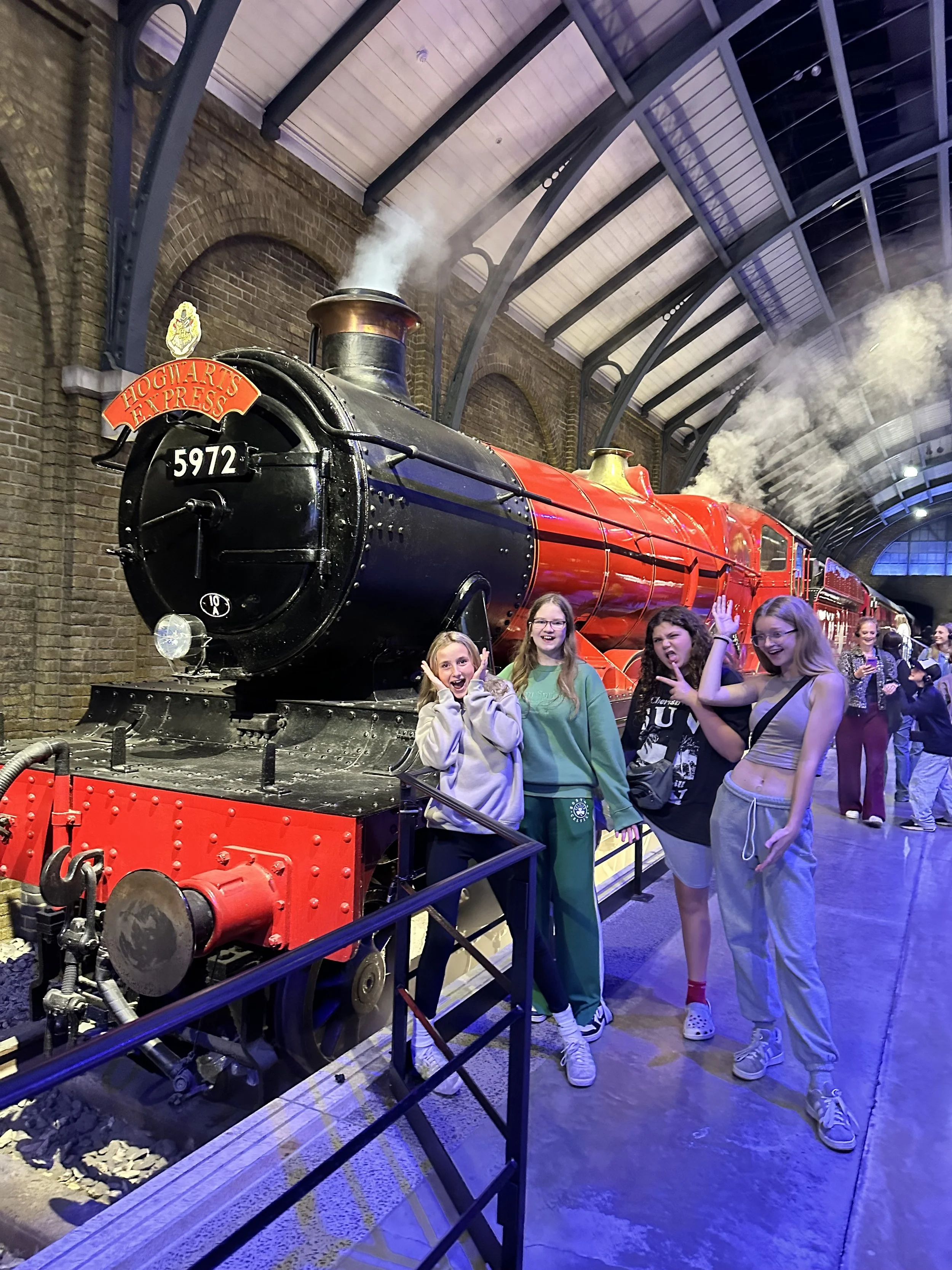 Four girls posing and smiling near a vintage Steam Locomotive at Harry Potter Warner Brothers Studios tour