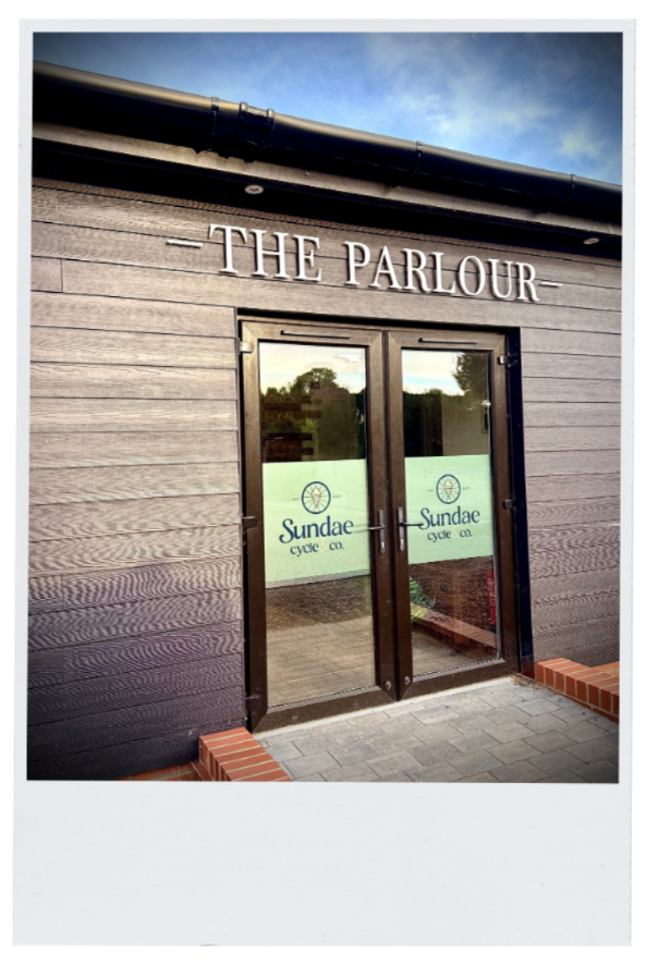 Exterior of a building with the sign 'The Parlour' and glass doors displaying 'Sundae Cycle Co.