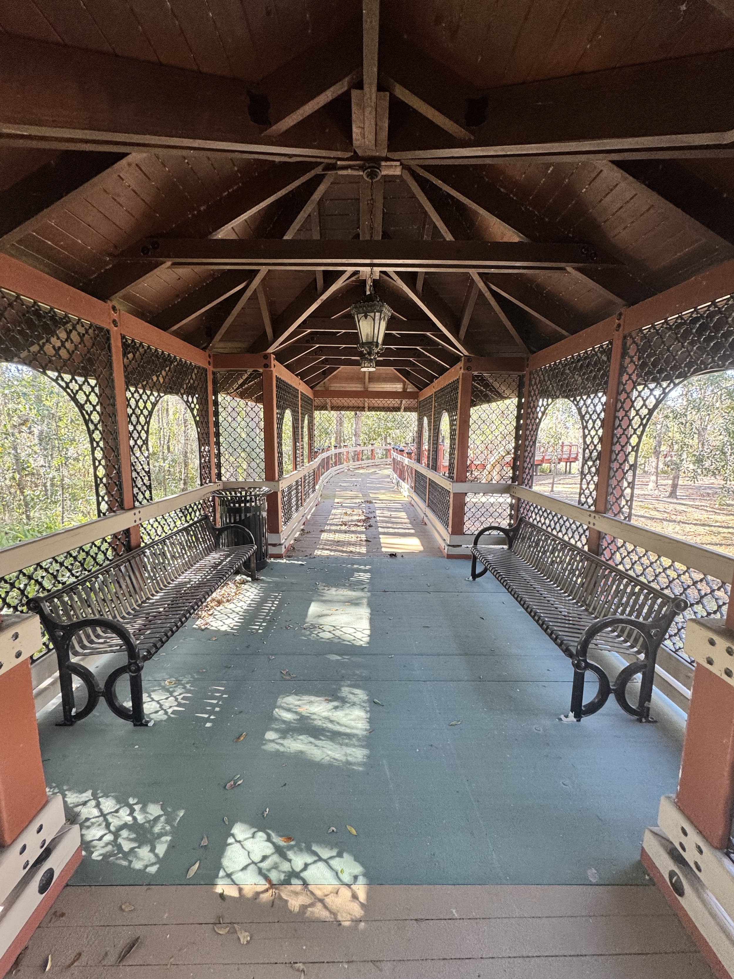 covered pavilion with benches, connecting from wood pedestrian bridge