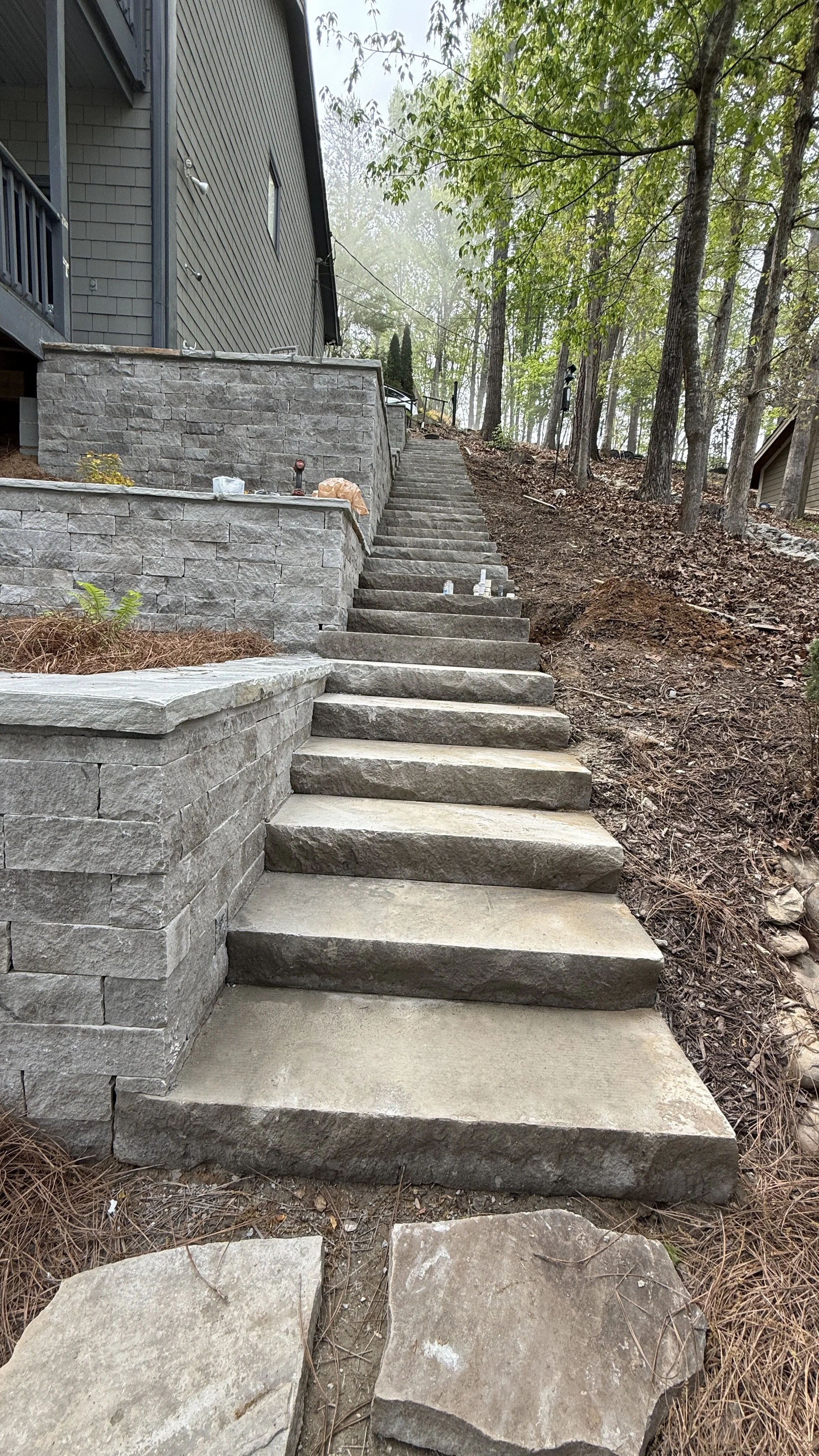Custom stone slab hillside staircase with block retaining walls built by Lawn Warriors in North Georgia