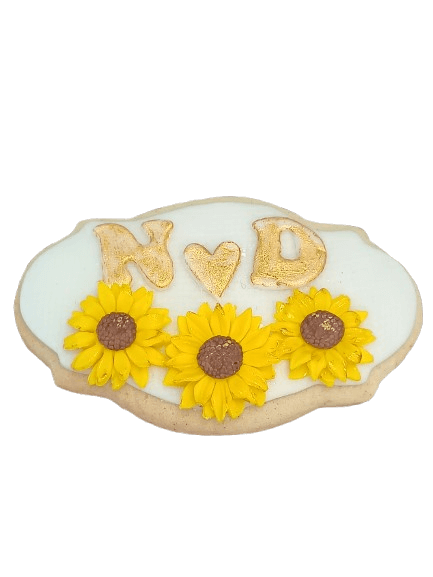 Decorative sugar cookie with white icing, yellow sunflower decorations, and the letters N and D with a heart symbol in between.