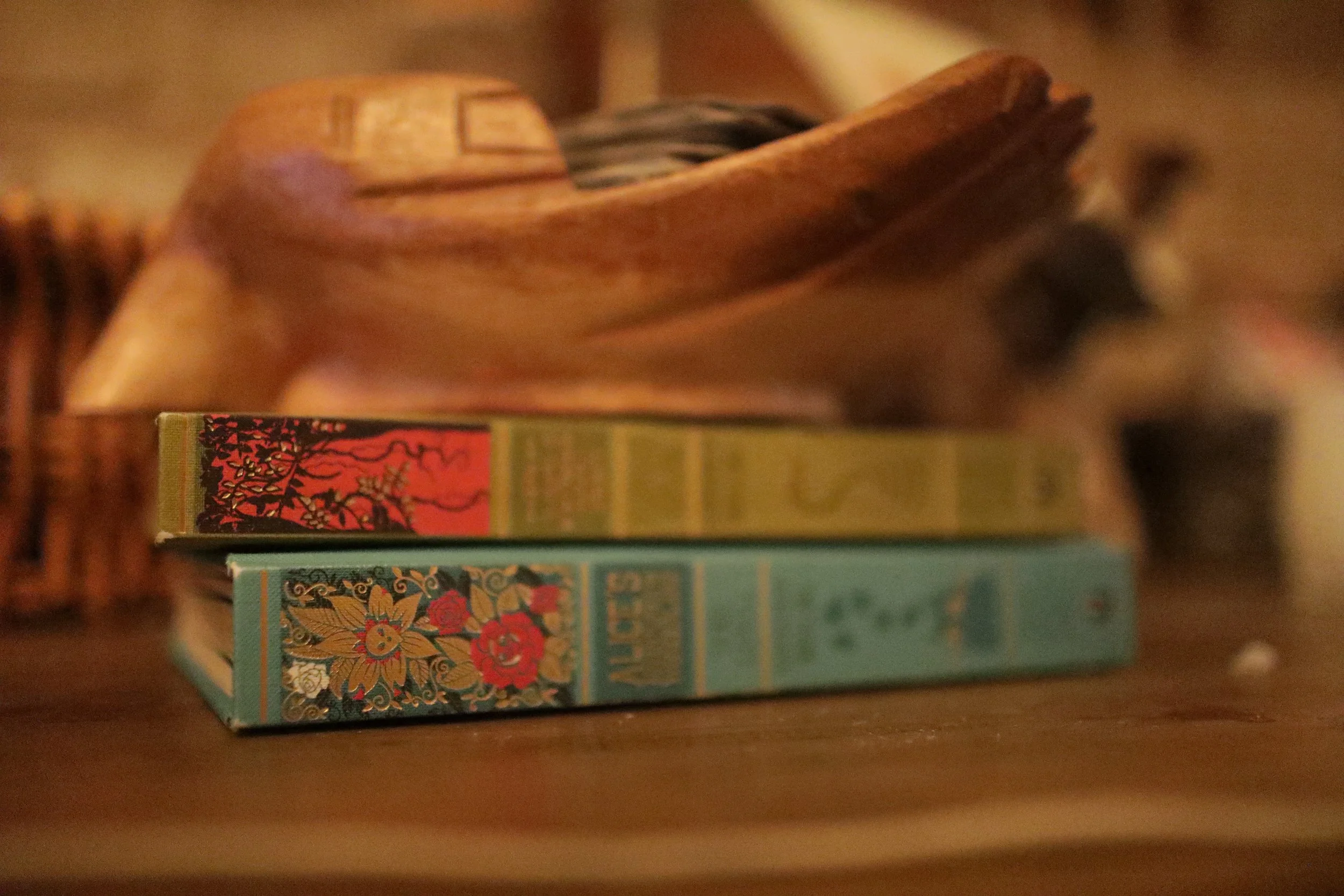 Stack of three books with decorative covers placed on a wooden surface.
