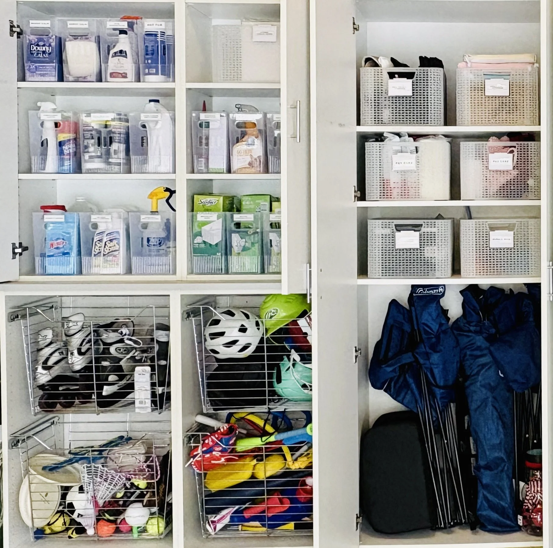 Garage cabinets with clear labeled bins on shelves and wire baskets holding helmets, balls, and sports gear