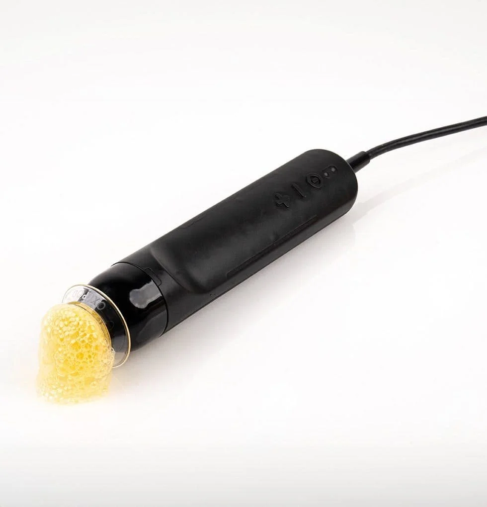 A black electronic device with a yellow sponge attachment at one end and a power cord, on a white background.