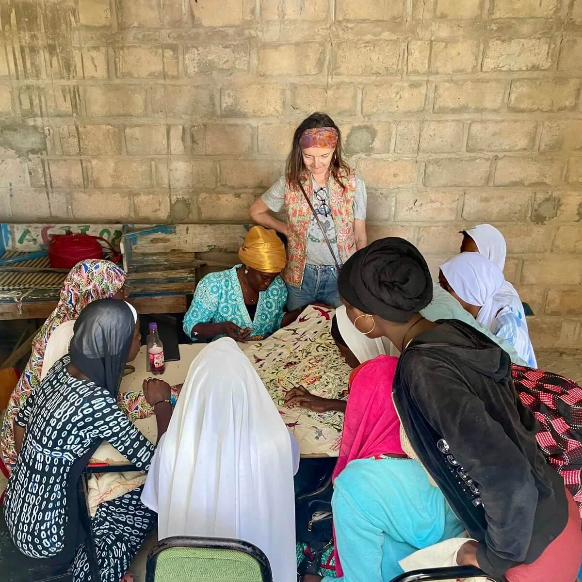 Amélie Rouyer, les jeunes filles de l'association Action Femme Enfant et leur enseignante Marie Diop travaille à la finalisation de la pièce brodée 'La conférence des oiseaux'.