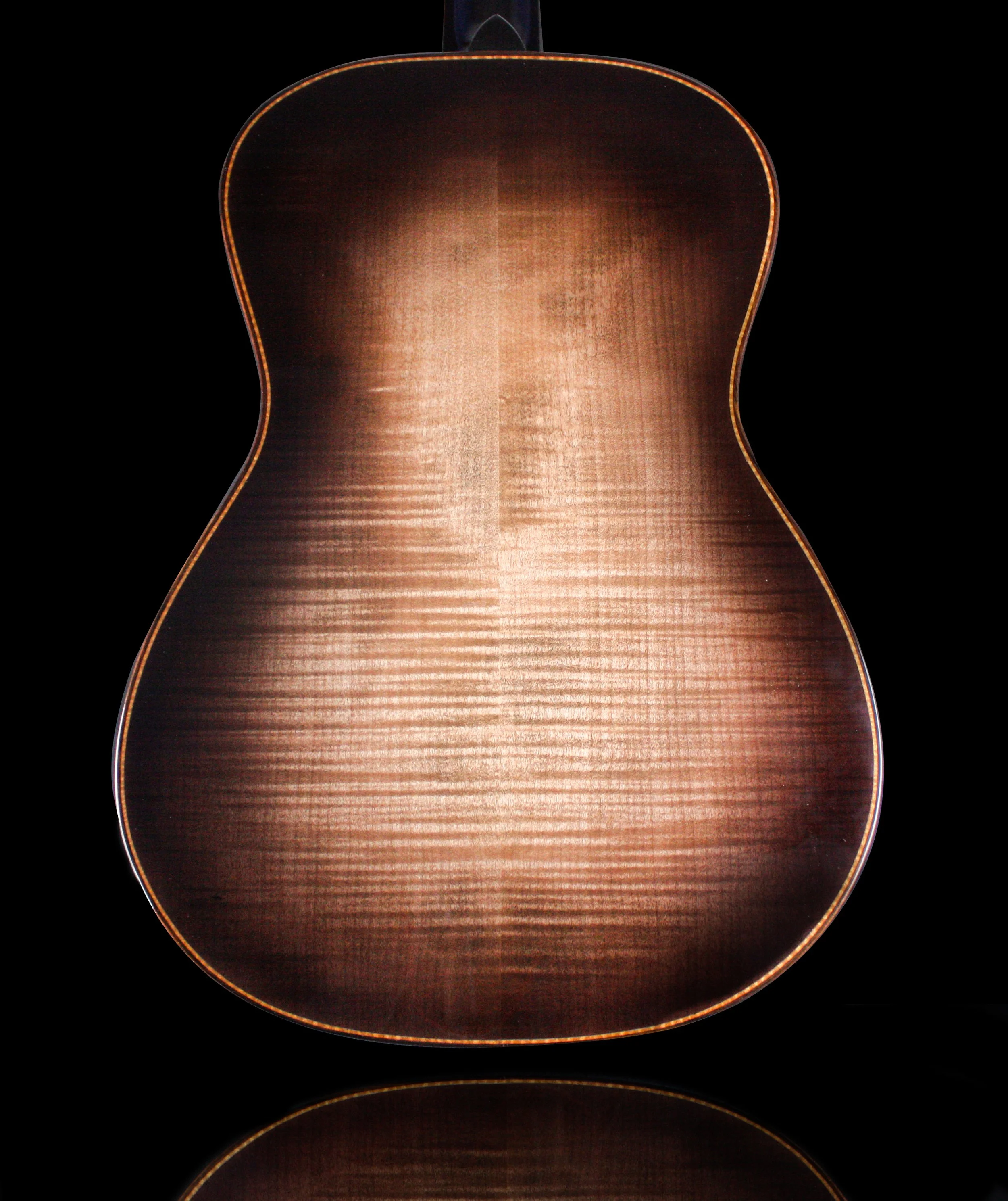 Back of a wooden acoustic guitar with a dark black background.