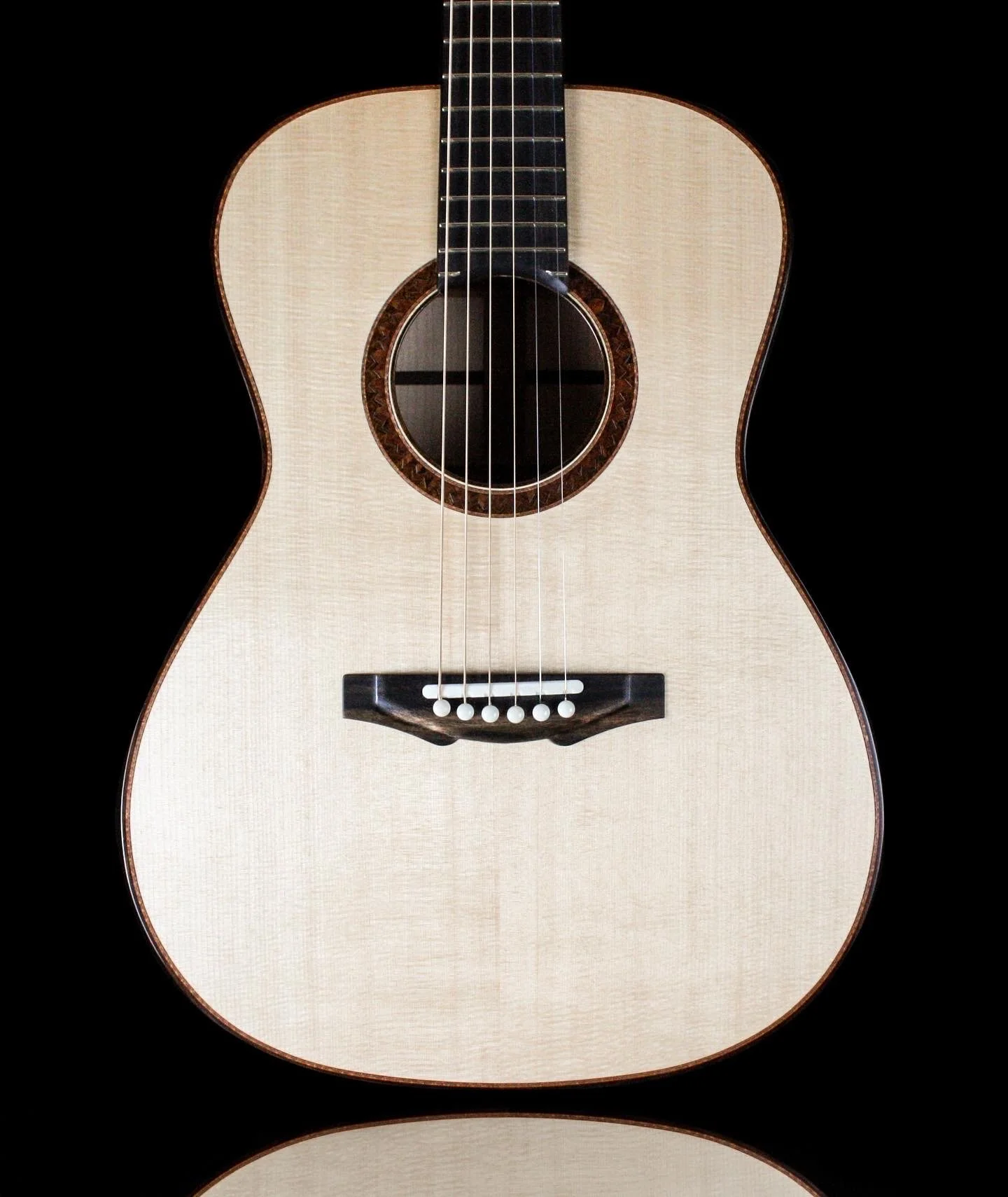 A close-up of an acoustic guitar against a black background.