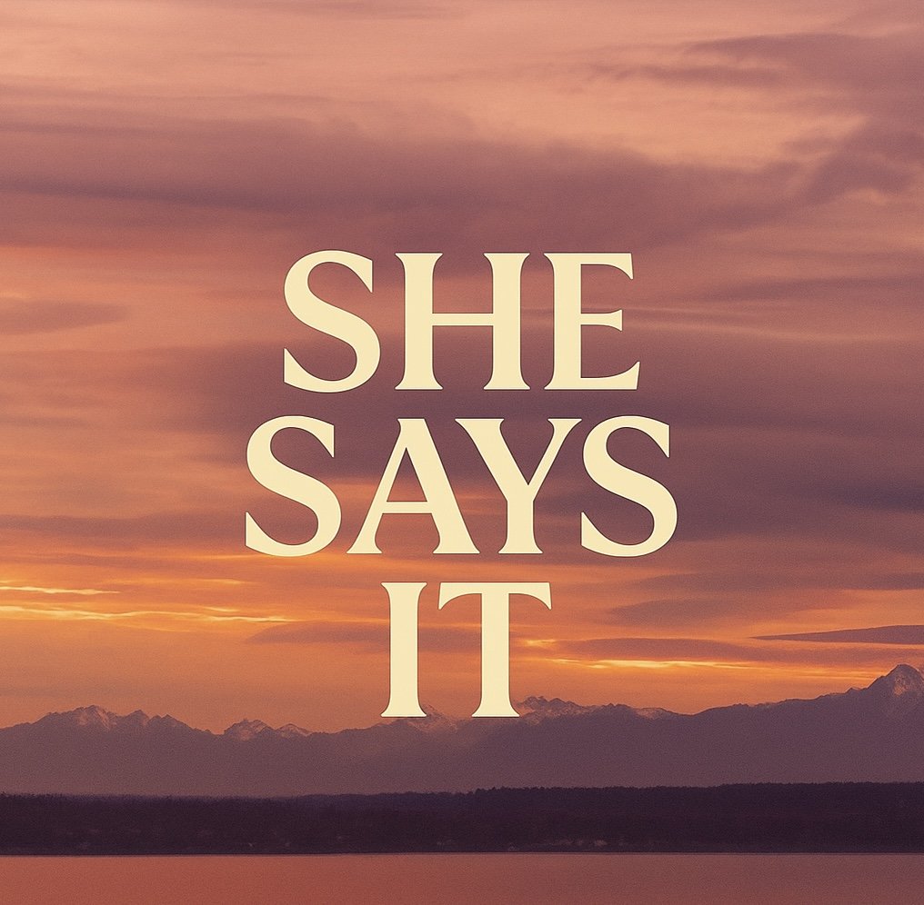 A sunset over mountains with the words 'SHE SAYS IT' in large, light-colored font in the center.