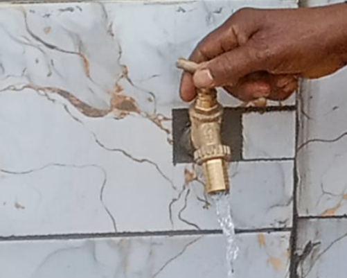 A hand turns the spigot of a faucet installed at a new community well -- this one in Mambu, Cameroon.