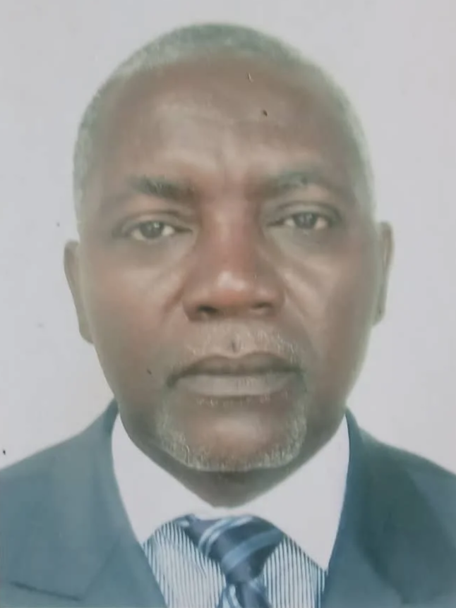A portrait photograph of an African man with gray hair, wearing a dark suit, white shirt, and striped tie.