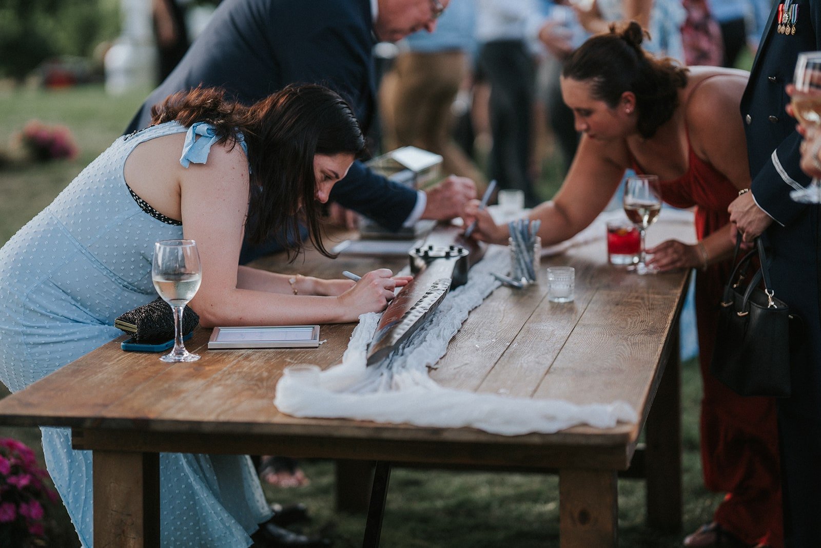 People signing a guest book at an outdoor event.