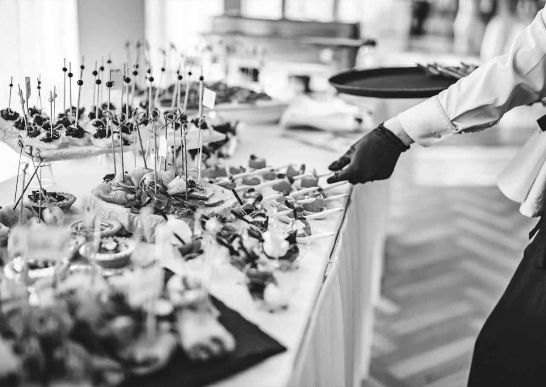 A buffet with various appetizers and finger foods, with a person serving themselves using tongs.
