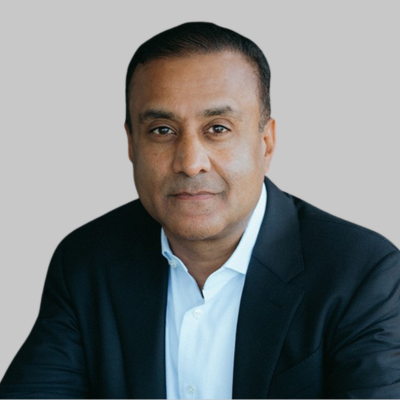 Portrait of a man in business attire, wearing a dark blazer and white shirt, against a dark background.