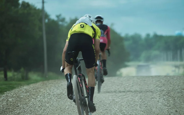 A gravel racer in yellow riding a dusty gravel road at Unbound, USA