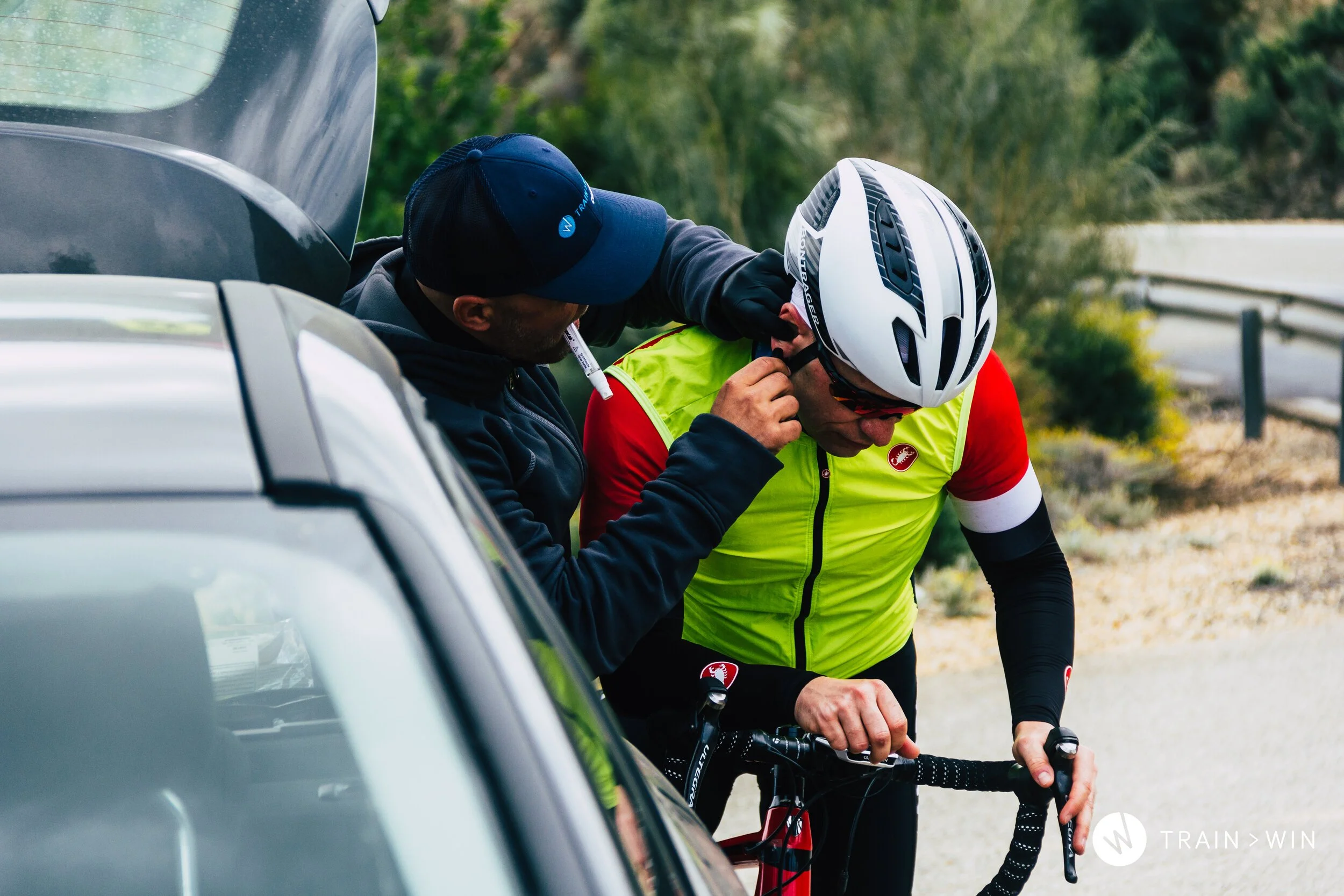 Coach Jānis Mūsiņš taking an ear-lobe lactate sample from a rider at the roadside during a road test