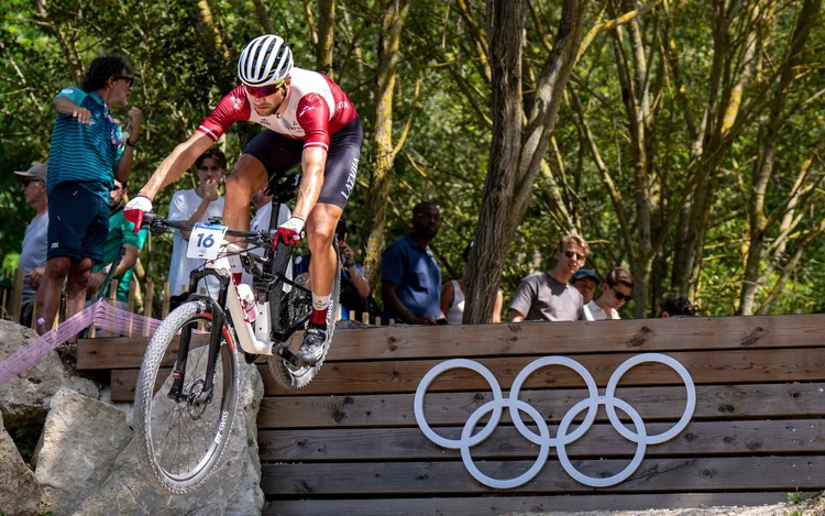 Mārtiņš Blūms jumping the Olympic rings drop at the Paris 2024 Olympic Games mountain bike race