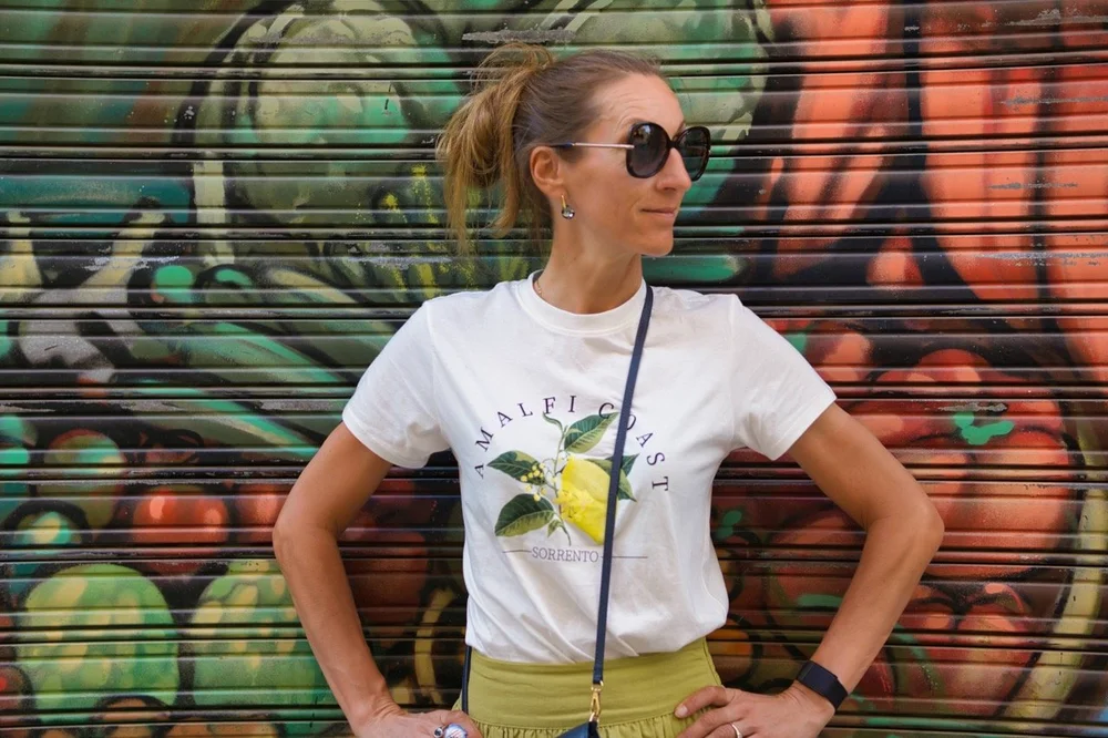 Dana Rožlapa off the bike, in a white T-shirt in front of a painted wall