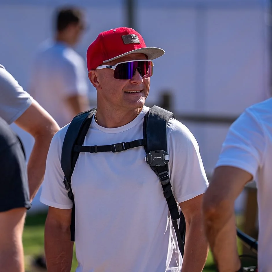 Jānis Mūsiņš smiling at a race venue with Latvian team staff