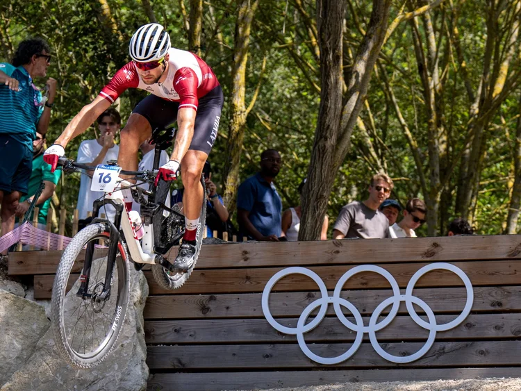 Mārtiņš Blūms jumping the Olympic rings drop at the Paris 2024 Olympic Games mountain bike race