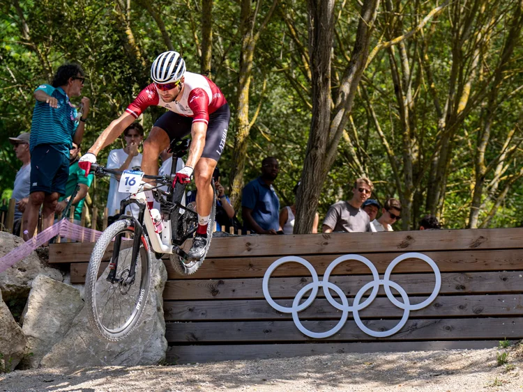Mārtiņš Blūms jumping the Olympic rings drop at the Paris 2024 Olympic Games mountain bike race