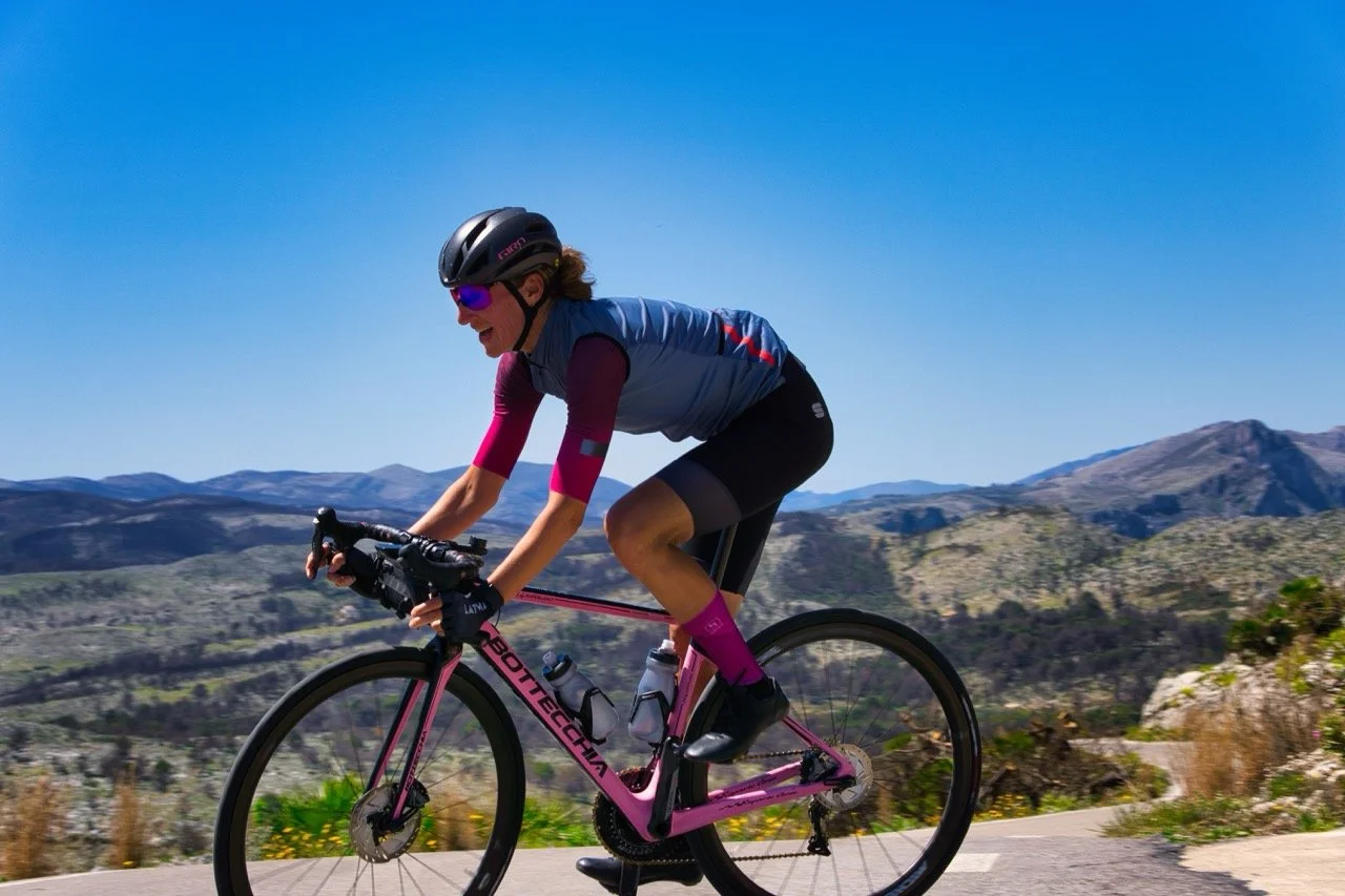 Dana Rožlapa riding her road bike on a sunny mountain road